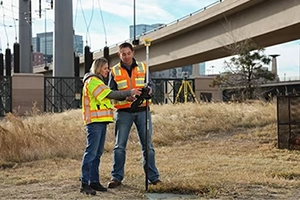 Field crew performing a topographic survey withTSC710 near power lines and a bridge
